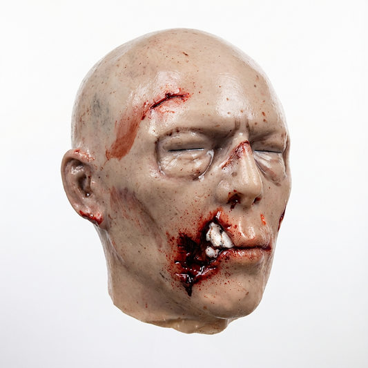 Flesh-tone ballistic gel zombie head with bloody wound detail, front view, on a white background